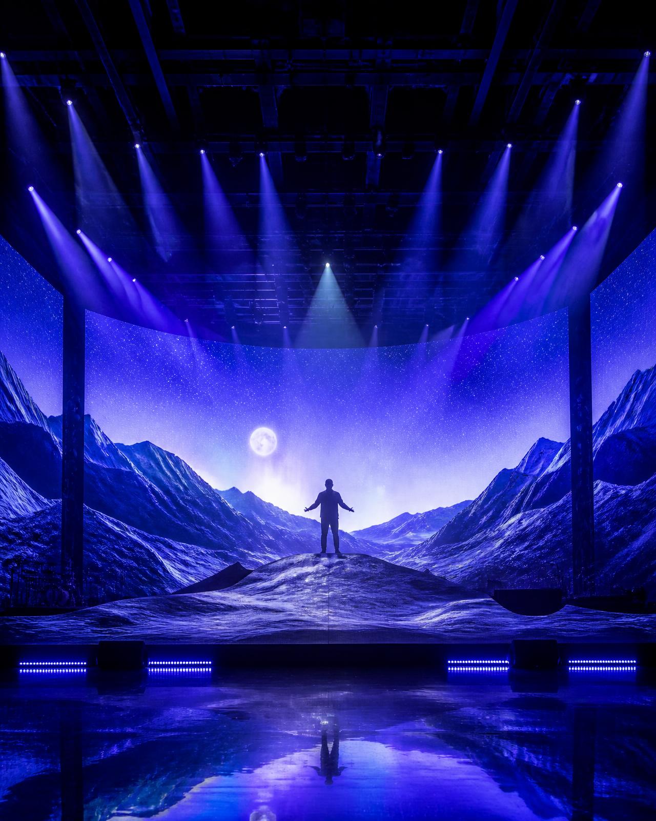 Rendered concert stage with volumetric light beams over dynamic terrain